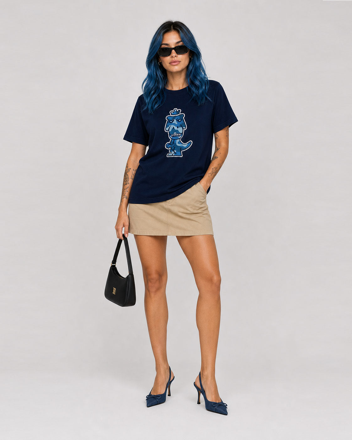 Woman with blue hair wearing navy blue Regno T-Rex Aeris pima cotton tee with luxury blue camo T-Rex graphic, bold monochrome NYC streetwear female lifestyle shot