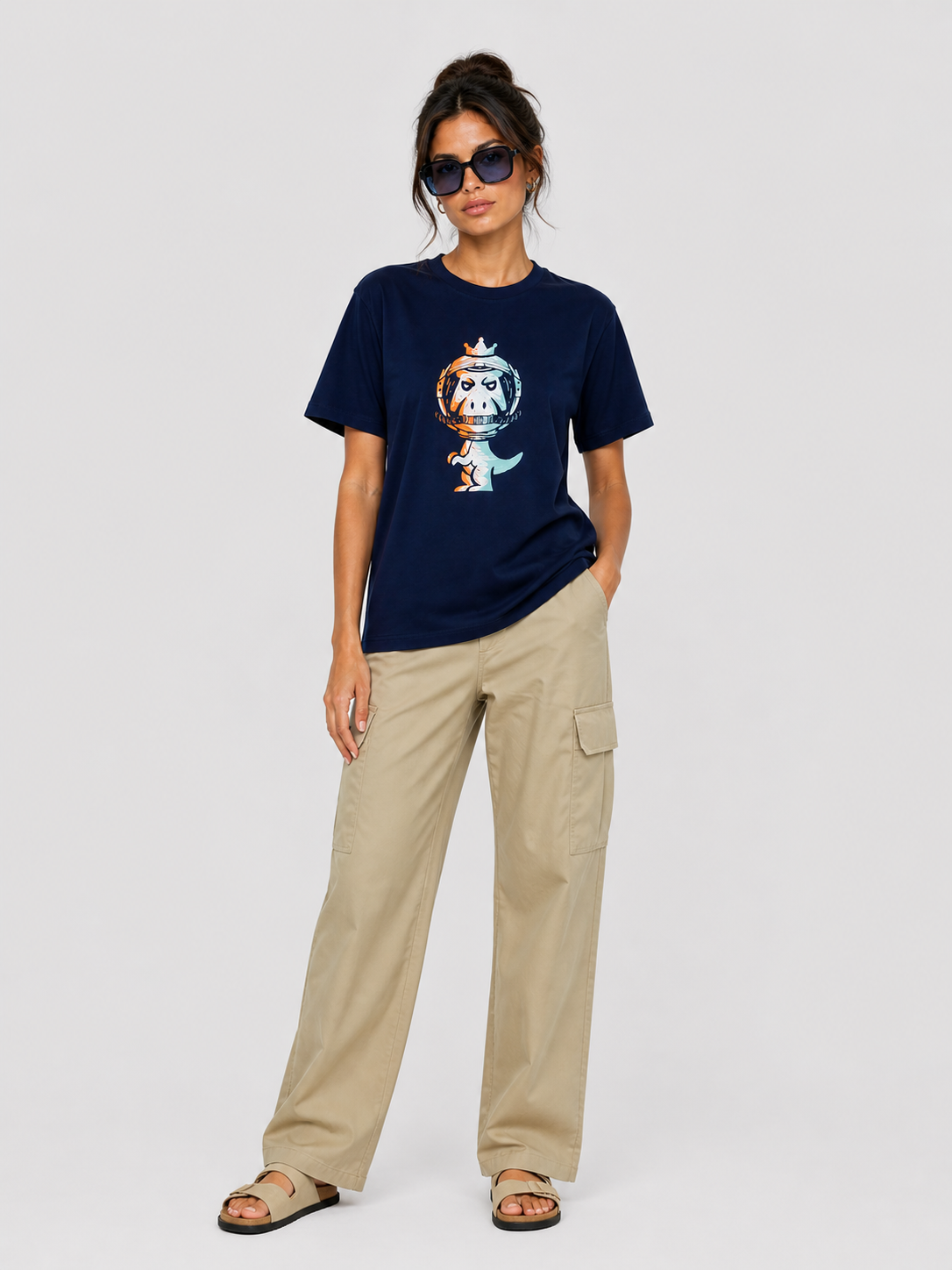 Woman wearing navy blue Regno T-Rex Astro pima cotton tee with cosmic graphic styled with beige wide leg cargo pants and sandals, casual luxury streetwear female outfit