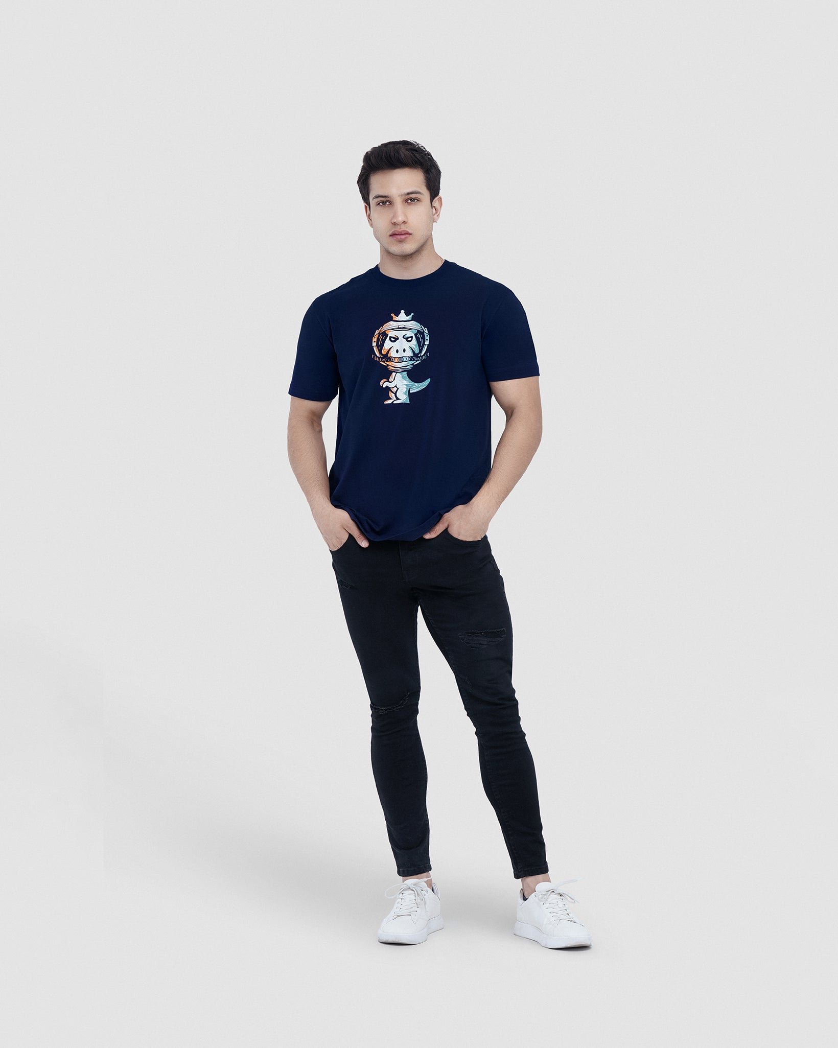 Man wearing navy blue Regno T-Rex Astro pima cotton t-shirt with cosmic orange and blue graphic, full body lifestyle shot
