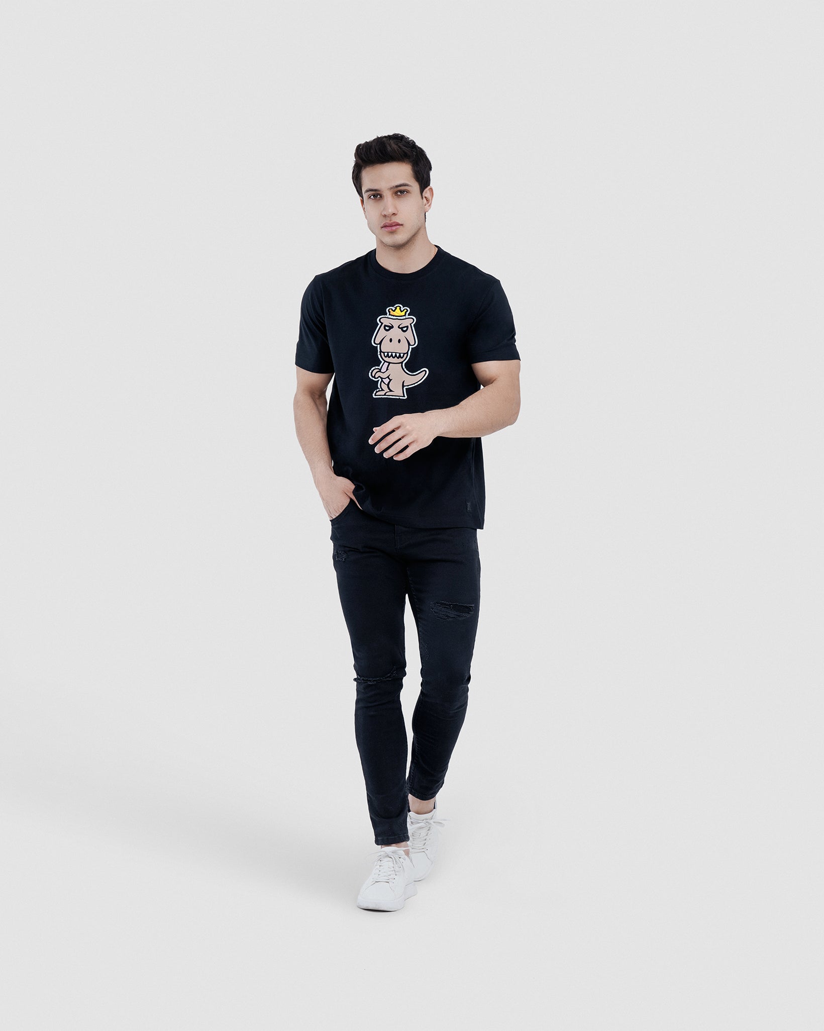 Man wearing black Regno Nudus pima cotton t-shirt with clean minimalist T-Rex graphic, full body lifestyle shot