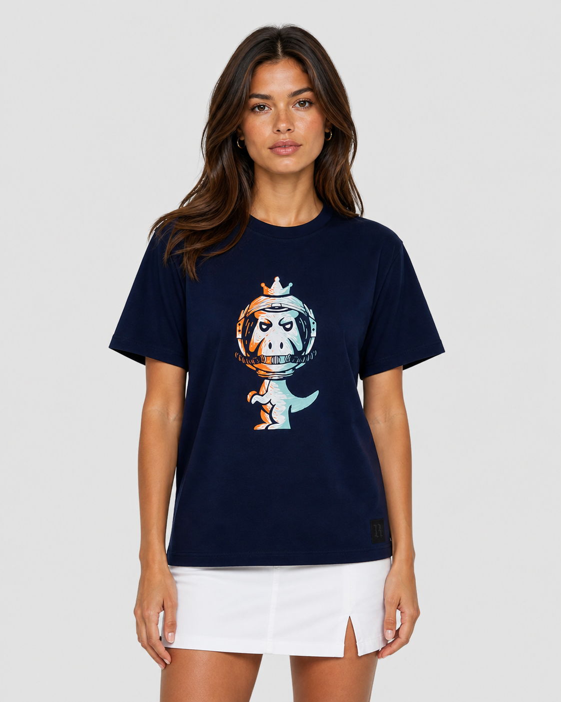 Woman wearing navy blue Regno T-Rex Astro pima cotton tee with cosmic orange and blue astronaut T-Rex graphic styled with white mini skirt, luxury streetwear female lifestyle shot