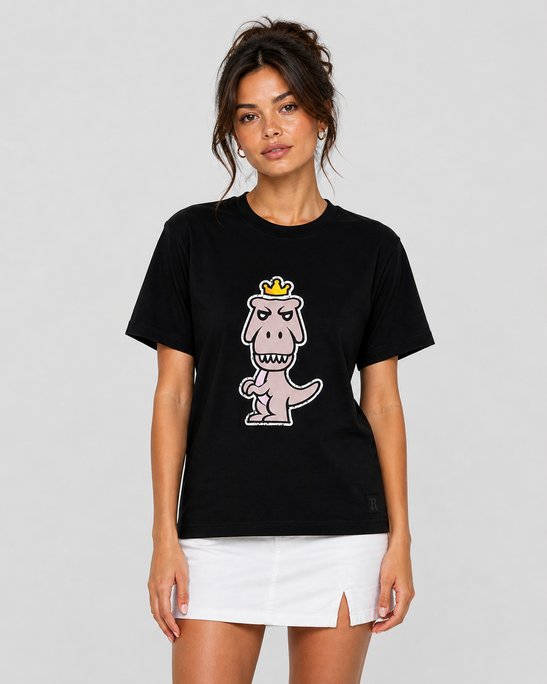 Woman wearing black Regno Nudus pima cotton luxury tee with minimalist pastel T-Rex graphic styled with white mini skirt, effortless streetwear female lifestyle shot