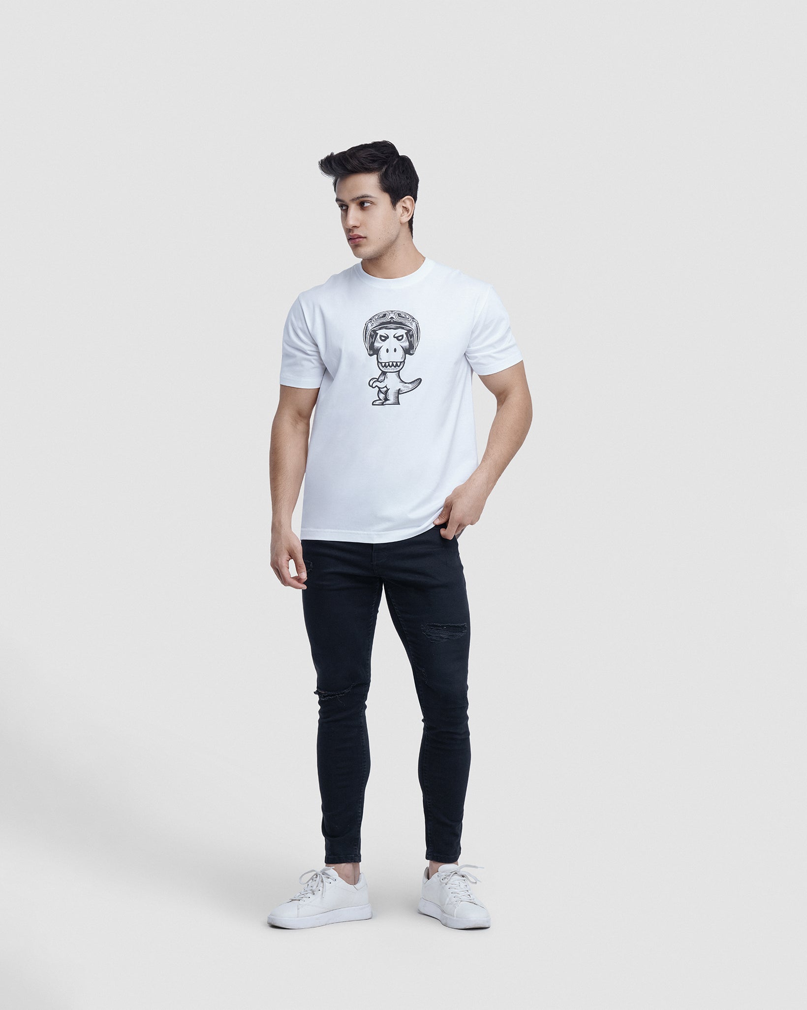 Man wearing white Regno T-Rex Birota pima cotton t-shirt with racing helmet graphic, full body lifestyle shot