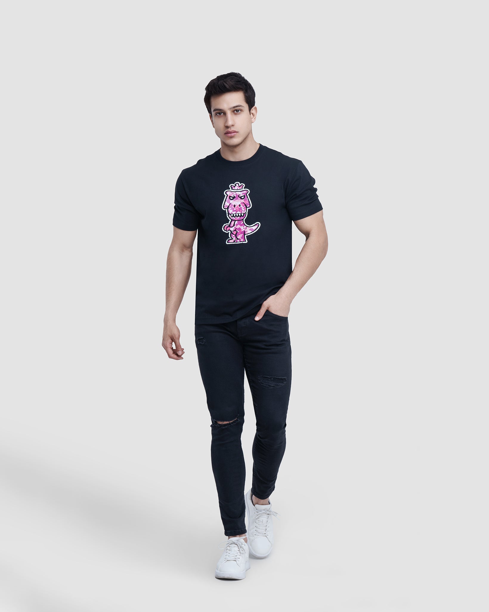 Man wearing black Regno T-Rex Rubesco pima cotton t-shirt with pink pixel arcade graphic, full body lifestyle shot